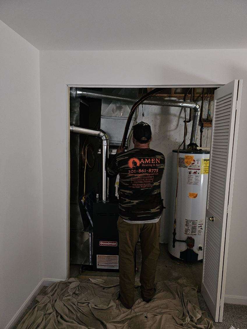 Amen HVAC technician servicing a furnace in a Southern Maryland home